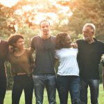 diverse people with arms on shoulders smiling at each other